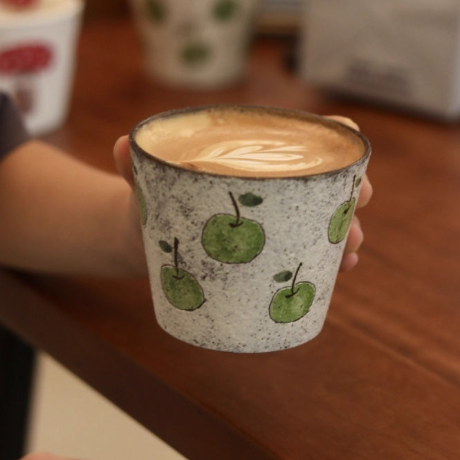 Handcrafted ceramic coffee cup with green apple pattern and purple clay interior – 280ml artisan mug on wooden table
