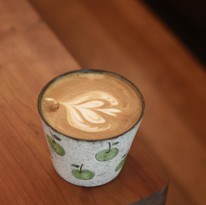 Handcrafted ceramic coffee cup with green apple pattern and purple clay interior – 280ml artisan mug on wooden table