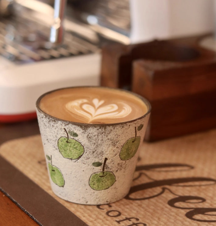 Handcrafted ceramic coffee cup with green apple pattern and purple clay interior – 280ml artisan mug on wooden table