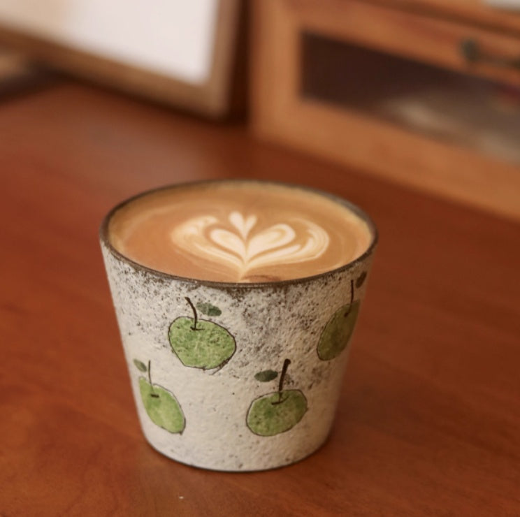 Handcrafted ceramic coffee cup with green apple pattern and purple clay interior – 280ml artisan mug on wooden table